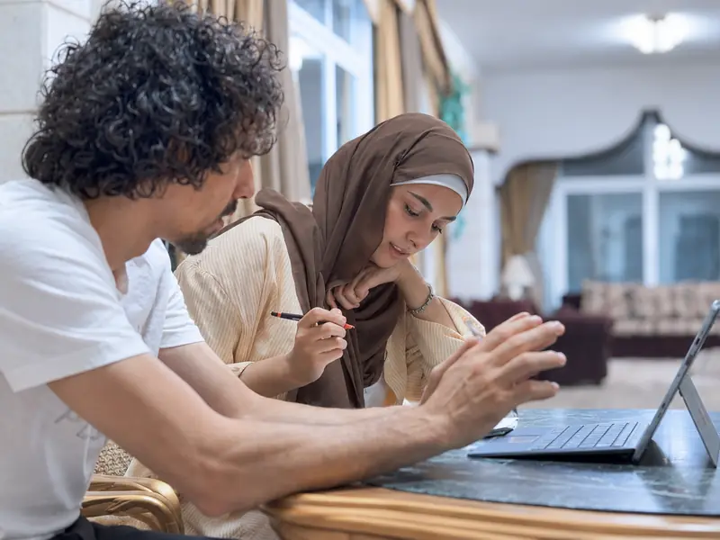 A teacher and a student work through a problem together on a laptop