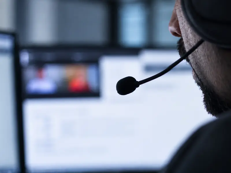 A teacher in a headset leads an online lesson with students on screen