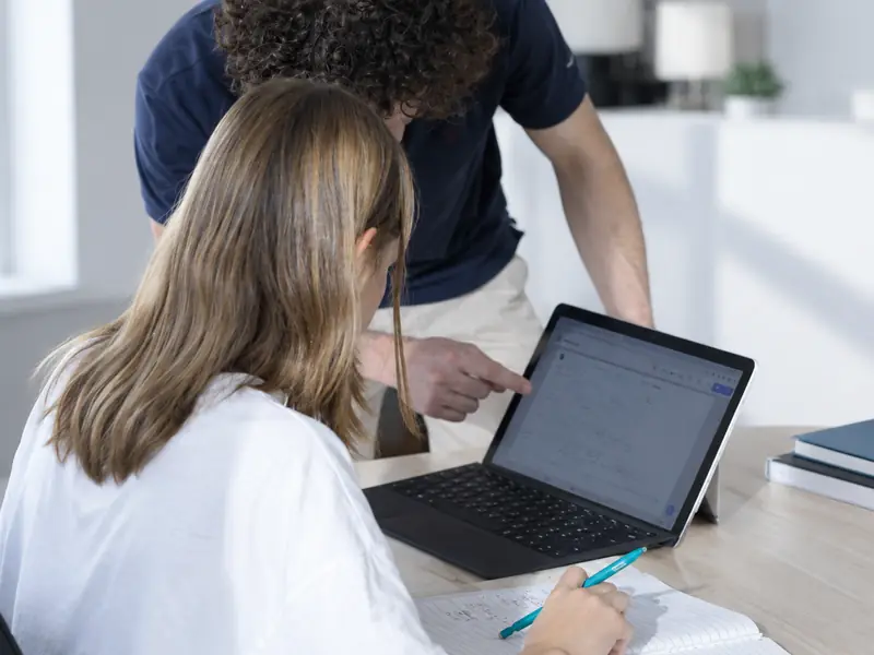 A teacher shows a student something on her laptop