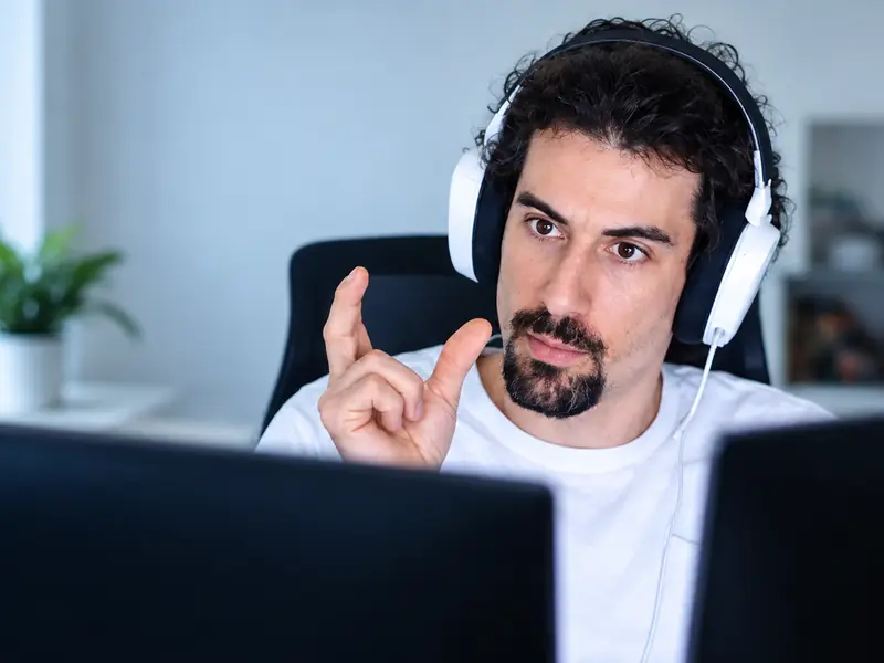 A teacher in headphones explains a step to a student on a video call